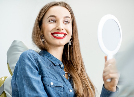 woman with red lipstick on smiling into mirror